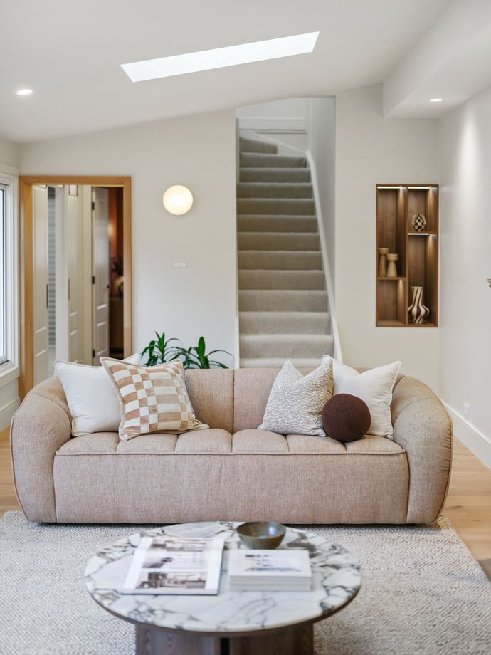 Light-filled living room with skylight, carpeted stair and curved sofa in a renovated terrace
