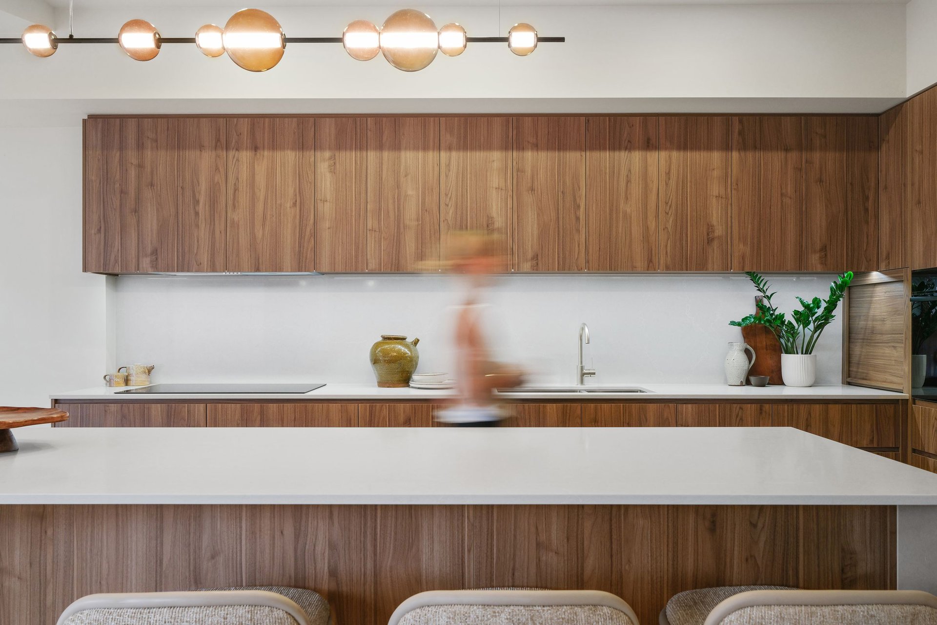 Renovated kitchen with walnut timber joinery, globe pendant light and stone island bench