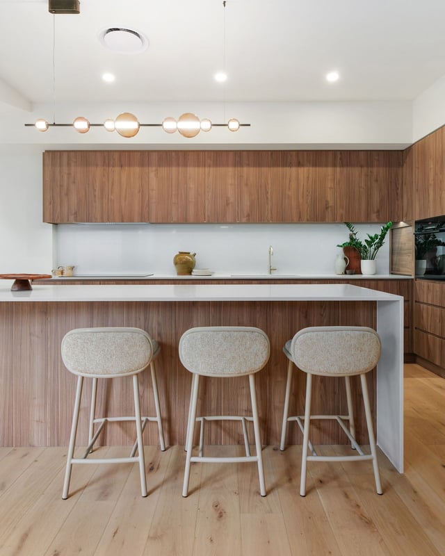 Timber kitchen island with upholstered stools and globe pendant