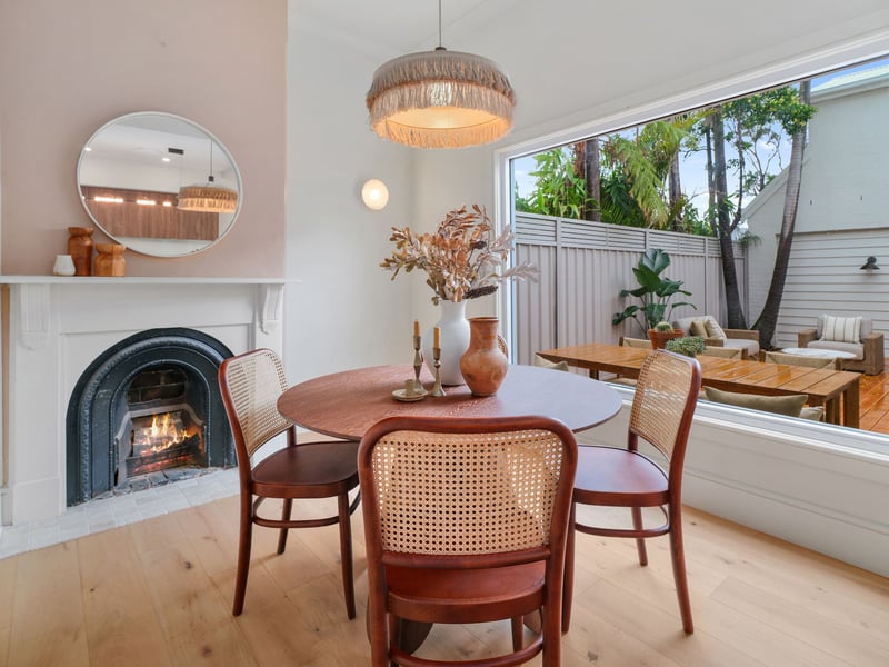 Dining room with restored fireplace, rattan chairs and a picture window to the garden